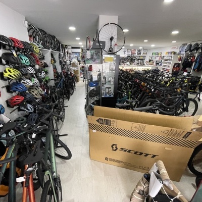 Loja de bicicletas com capacetes coloridos na parede e caixa de papelão SCOTT no chão