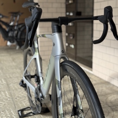 Bicicleta de estrada cinza e verde com guiador preto e pneus Schwalbe One Performance