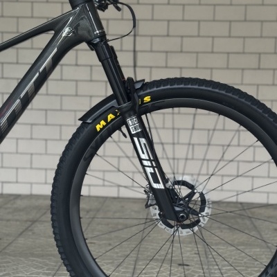 Roda dianteira de bicicleta de montanha preta com suspensão e pneu.