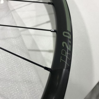 Roda de bicicleta preta com inscrição TR 2.0 em superfície branca