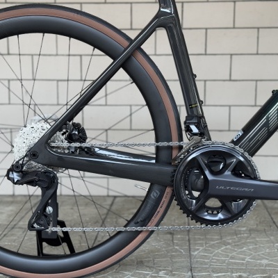 Sistema de transmissão de bicicleta preta com pneus castanhos claros e fundo de parede branca