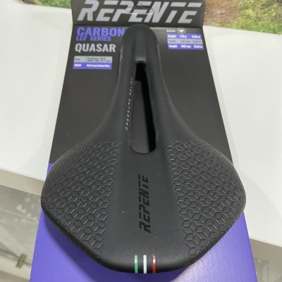 Selim de bicicleta preto com textura hexagonal e recorte central em embalagem preta e roxa