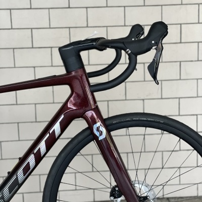 Bicicleta de estrada castanha e preta contra parede de azulejos brancos