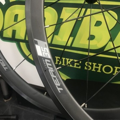 Rodas de bicicleta cinza escuro com etiquetas TEAM 35C e fundo de cartaz verde e amarelo