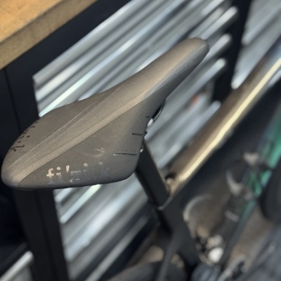 Selim de bicicleta fizik cinza escuro montado em bicicleta preta