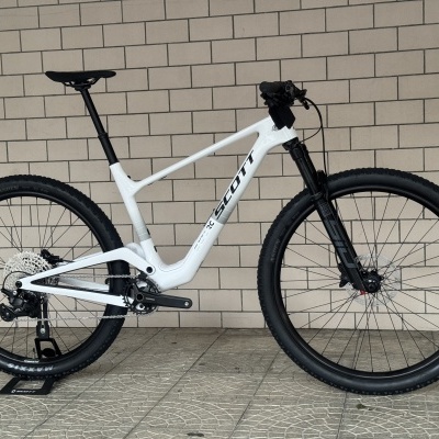 Bicicleta de montanha branca da marca SCOTT encostada a parede de tijolos