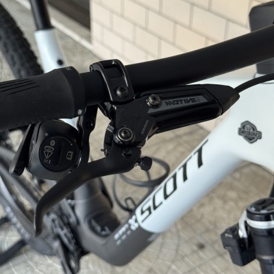 Bicicleta SCOTT branca e preta com guiador preto e travão SRAM Motive em parede com azulejos