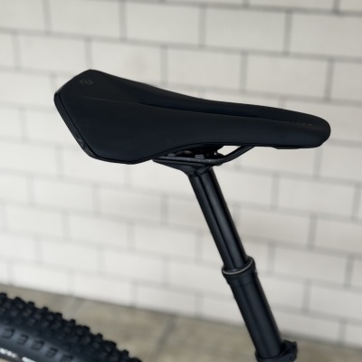 Selim de bicicleta preto com canote preto ajustável e parte do quadro branco da bicicleta