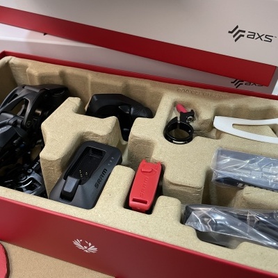 Componentes de sistema de transmissão de bicicleta da marca AXS organizados em caixa aberta