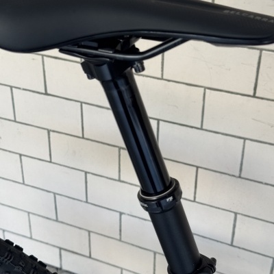 Sela preta de bicicleta com canote preto em fundo de parede de azulejos brancos