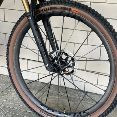 Roda de bicicleta com pneu Schwalbe Wicked Will 29x2.25 preto e castanho, aro carbono, garfo suspensão e disco travão