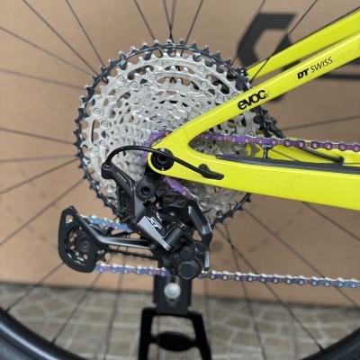 Roda traseira de bicicleta com corrente colorida, cassete metálico, desviador Shimano e quadro amarelo