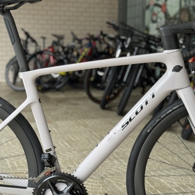 Bicicleta de estrada branca com quadro SCOTT e rodas pretas num armazém de bicicletas