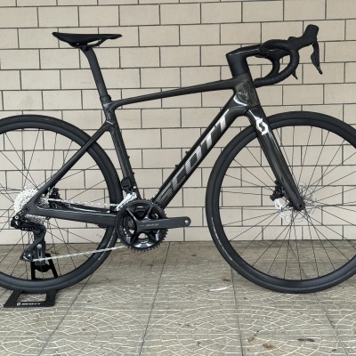 Bicicleta de estrada Scott preta em carbono com rodas Schwalbe e grupo Shimano 105