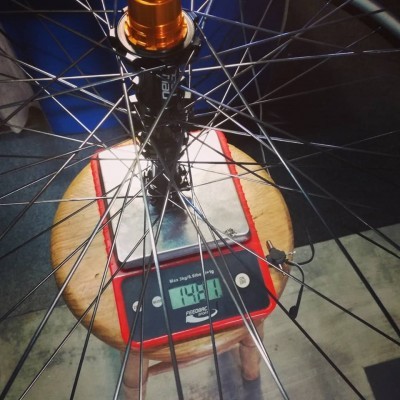 Roda de bicicleta sobre balança digital vermelha sobre banco de madeira, peso 1490 g