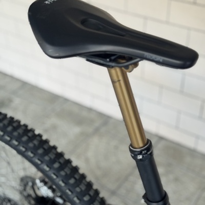 Selim preto de bicicleta com cubo dourado e pneus pretos em fundo branco