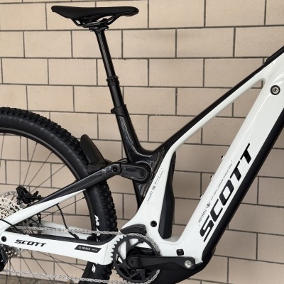 Bicicleta de montanha elétrica branca e preta SCOTT próxima a uma parede de azulejos