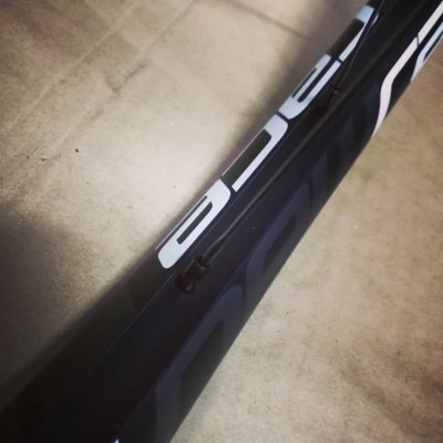 Parte de quadro de bicicleta preto com gráficos brancos em fundo cinza