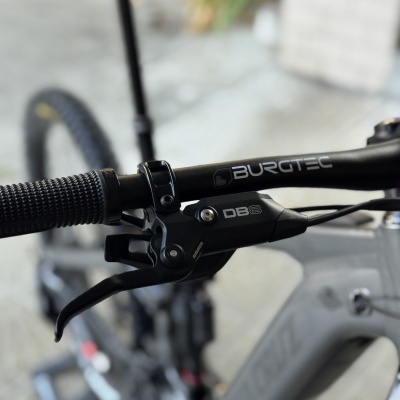Punho e manete de travão bicicleta com texto BURGTEC e DBS em fundo desfocado