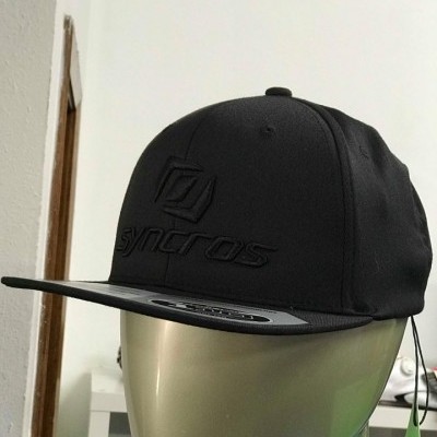 Boné preto com logótipo 'syncros' exibido em cabeça de manequim dourada
