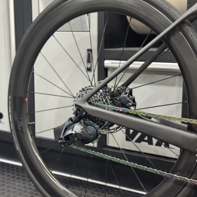 Roda traseira de bicicleta com aro preto, pneu Schwalbe, corrente multicolorida e mudanças eletrónicas