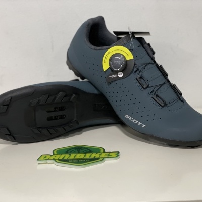 Sapatilhas de ciclismo Scott azul escuro com fecho em disco e sola preta sobre superfície branca com autocolante Dunbikes.