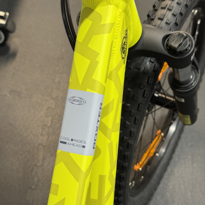 Bicicleta de montanha amarela com texto no tubo dianteiro e suspensão dianteira.