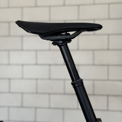 Selim de bicicleta negro com espigão ajustável em frente a parede de tijolos cinzentos