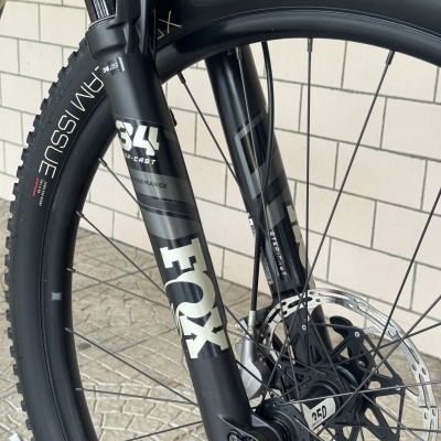 Pneu e garfo dianteiro de bicicleta de montanha preto com etiquetas e disco de travão.
