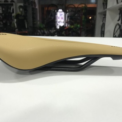 Sela de bicicleta bege com estrutura preta sobre mesa branca