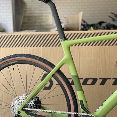 parte traseira de bicicleta de estrada verde com selim preto e pneus castanhos junto a caixa de cartão