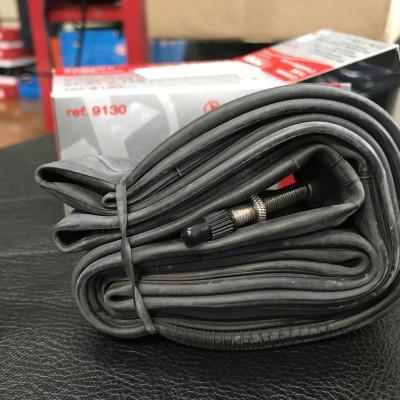 Câmara de ar preta dobrada com válvula metálica e caixa com texto ref. 9130 ao fundo