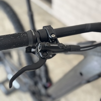 Punho de bicicleta preta com manete de travão Shimano e detalhes em cinza do quadro.