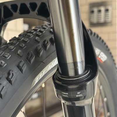 Pneu de bicicleta todo-o-terreno preto com garfo de suspensão metálico e etiqueta com especificações