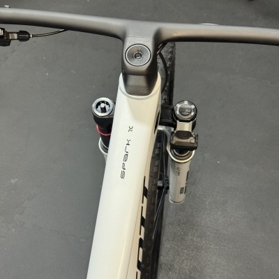 Bicicleta branca com guiador preto e suspensão RockShox vista de cima