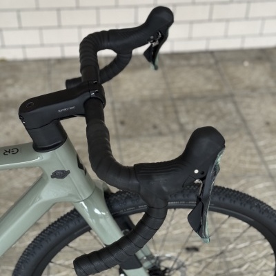 Bicicleta cinza com guiador curvo preto e pneus largos em ambiente interior