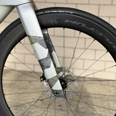 Roda dianteira de bicicleta com garfo cinzento claro e padrão geométrico