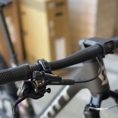 Guiador preto de bicicleta Scott com manete de travão e quadro cinzento com letras brancas.