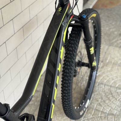 Bicicleta de montanha Scott preto e amarelo com suspensão dianteira junto a parede de azulejos.