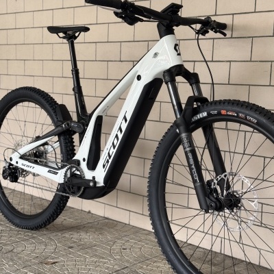 Bicicleta de montanha eléctrica branca e preta SCOTT junto a uma parede de tijolos