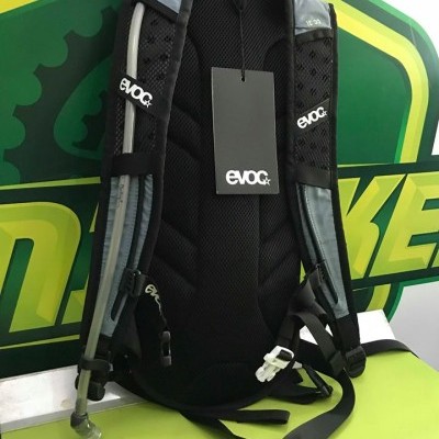 Mochila de hidratação EVOC preta e cinza com tubo transparente e etiqueta preta