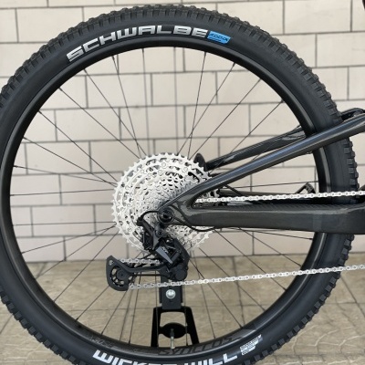 Pneu de bicicleta preto com texto Schwalbe e Wicked Will e roda com corrente e componentes