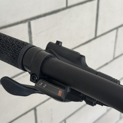 Punho com mudanças de velocidade de bicicleta preta com guiador e azulejos brancos ao fundo