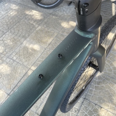 Quadro de bicicleta verde escura fosca com guiador preto, roda preta e piso de mosaico cinzento