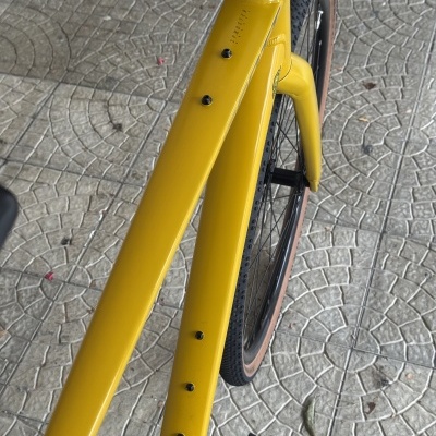 Quadro de bicicleta amarela com texto e pneus em piso pavimentado