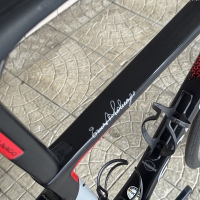 Bicicleta de estrada preta com detalhes vermelhos e brancos e texto Ernesto Colnago