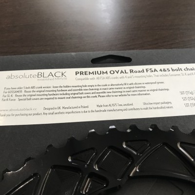 Etiqueta de papel com texto técnico sobre peça de bicicleta preta oval