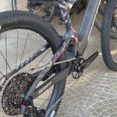 Bicicleta de montanha cinzenta e preta com detalhes rosa, roda traseira e pedaleira SCOTT.