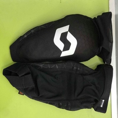 Protetores de joelho pretos com logo branco sobre superfície verde