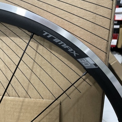 Roda de bicicleta preta e metalizada com escrita TRIMAX 30 em fundo de cartão